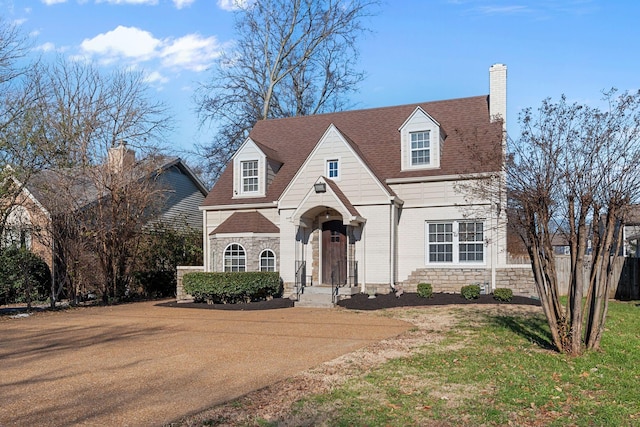 view of front of house with a front yard, fence, a shingled roof, a chimney, and stone siding