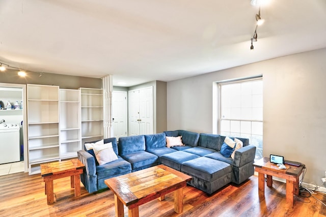 living room featuring washer / clothes dryer, track lighting, and wood-type flooring