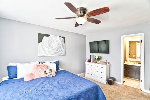 bedroom featuring ceiling fan, ensuite bathroom, light carpet, and sink