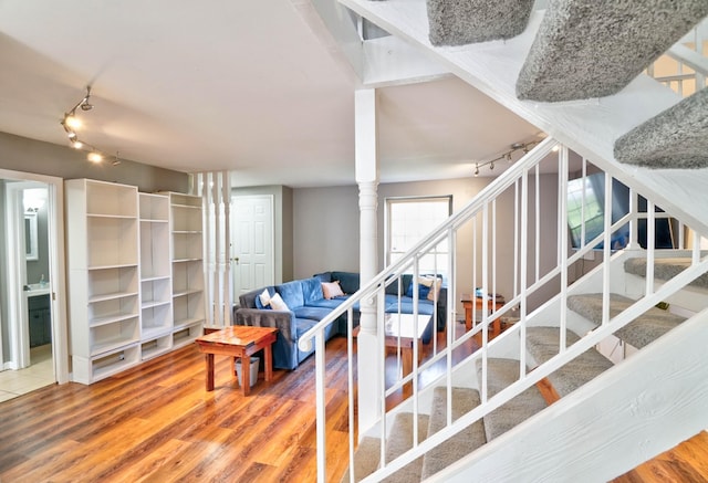 stairway featuring track lighting, decorative columns, and wood-type flooring