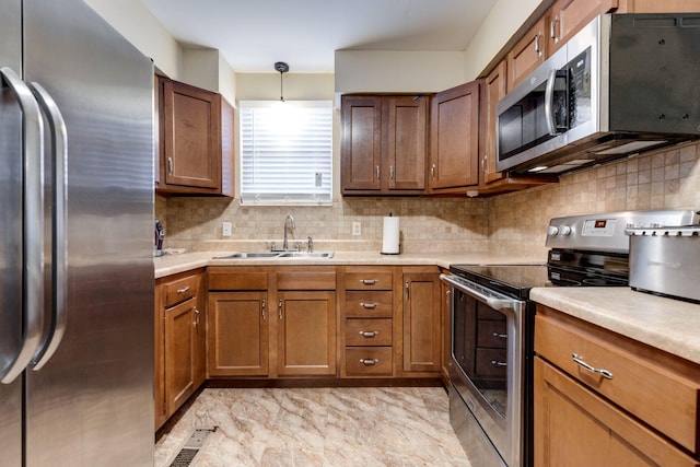 kitchen with sink, decorative backsplash, pendant lighting, and appliances with stainless steel finishes