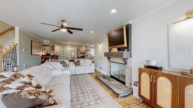 living room featuring a brick fireplace, ceiling fan, crown molding, and light hardwood / wood-style flooring