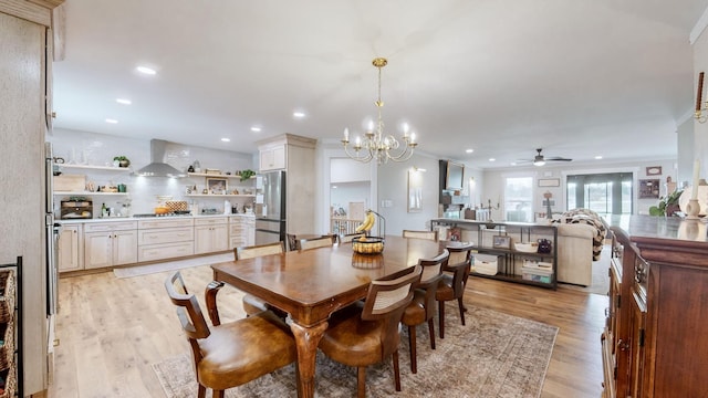 dining space with light hardwood / wood-style flooring and ceiling fan with notable chandelier