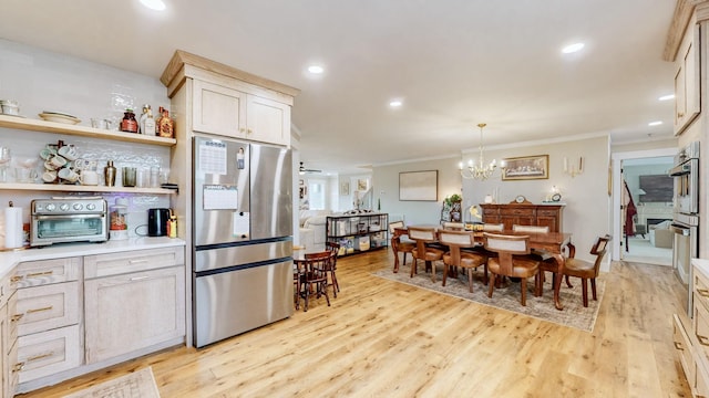 kitchen with light hardwood / wood-style flooring, decorative light fixtures, ceiling fan with notable chandelier, appliances with stainless steel finishes, and ornamental molding