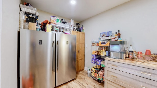 kitchen with butcher block countertops, light wood-type flooring, light brown cabinetry, and stainless steel refrigerator