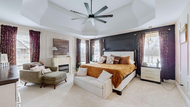 carpeted bedroom with ceiling fan and a raised ceiling