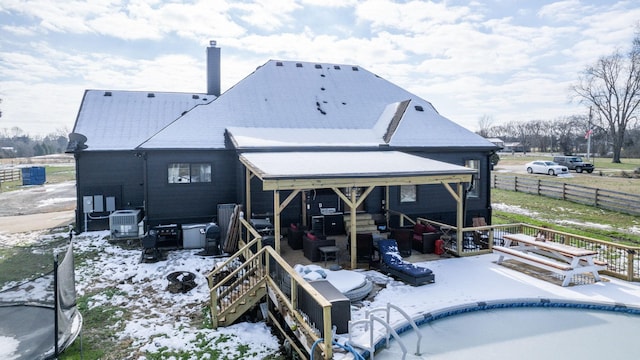 rear view of property with cooling unit and an empty pool