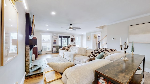 living room with ceiling fan, light wood-type flooring, crown molding, and a fireplace