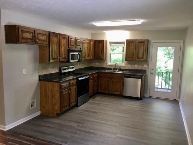 kitchen featuring stainless steel appliances, dark wood-type flooring, a wealth of natural light, and sink