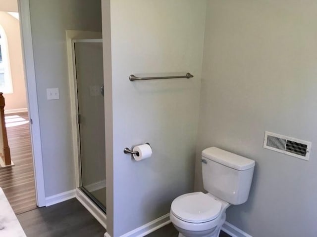 bathroom with wood-type flooring, an enclosed shower, and toilet