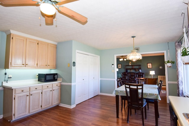 kitchen with black appliances, hanging light fixtures, ceiling fan with notable chandelier, and dark wood-type flooring