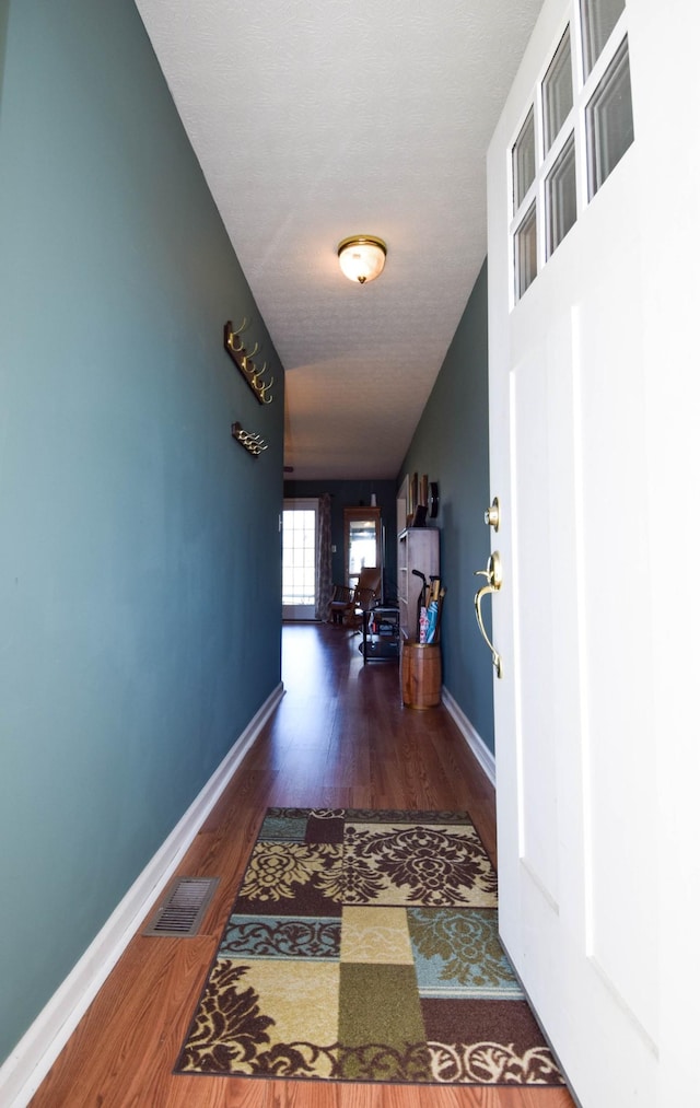 corridor featuring a textured ceiling and dark hardwood / wood-style flooring