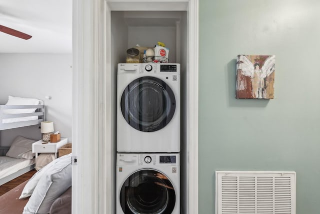 laundry area with wood-type flooring, ceiling fan, and stacked washer / dryer