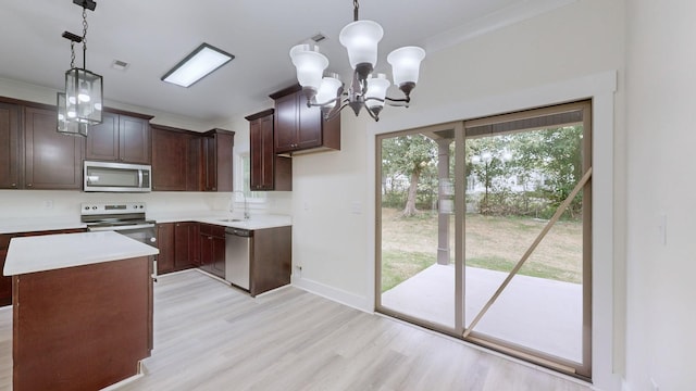 kitchen featuring an inviting chandelier, light wood-type flooring, a kitchen island, pendant lighting, and appliances with stainless steel finishes