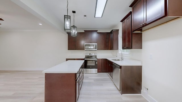 kitchen with stainless steel appliances, sink, decorative light fixtures, light hardwood / wood-style floors, and a kitchen island