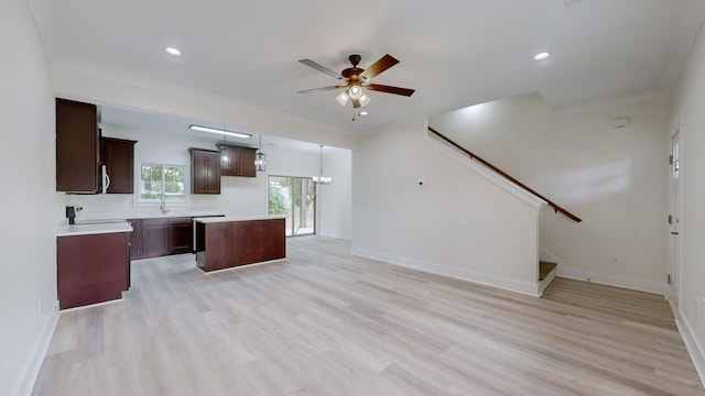 kitchen featuring decorative light fixtures, a kitchen island, light wood-type flooring, crown molding, and ceiling fan