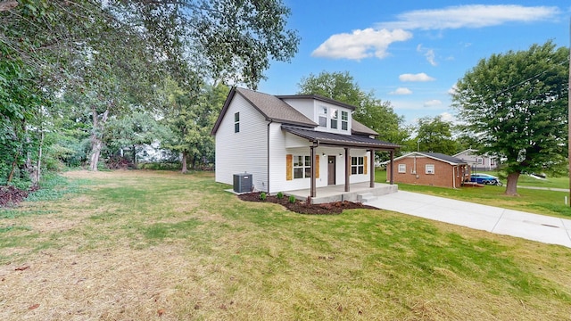 view of front of property with covered porch, central air condition unit, and a front yard