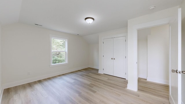 unfurnished bedroom with a closet, vaulted ceiling, and light hardwood / wood-style floors