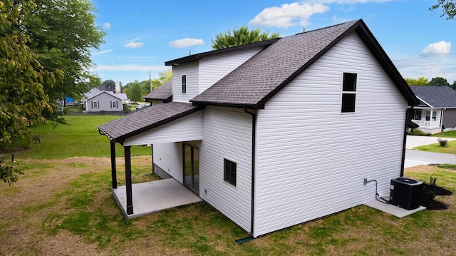 view of side of property featuring central AC, a yard, and a patio