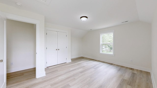 unfurnished bedroom featuring lofted ceiling, a closet, and light hardwood / wood-style flooring