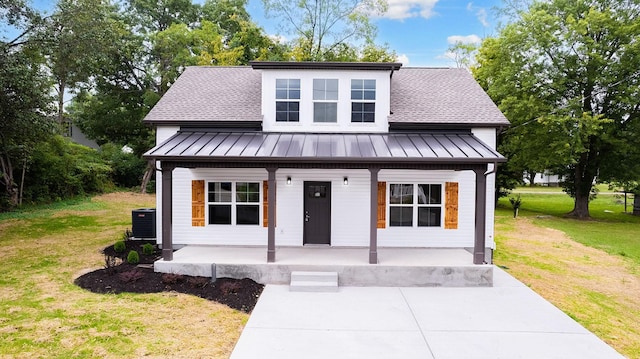 view of front of house with a front yard, a porch, and central AC