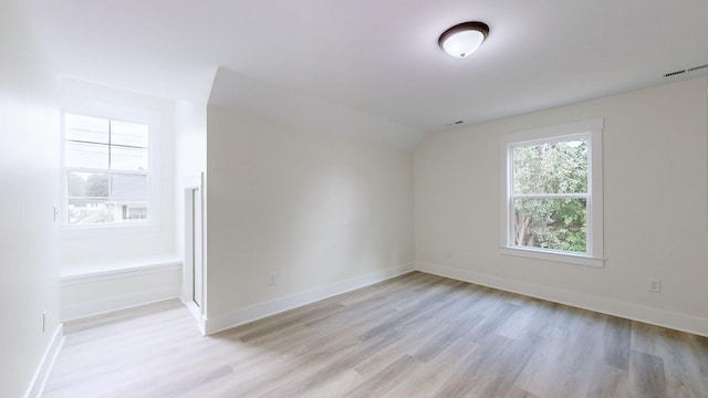 unfurnished room with light wood-type flooring and vaulted ceiling