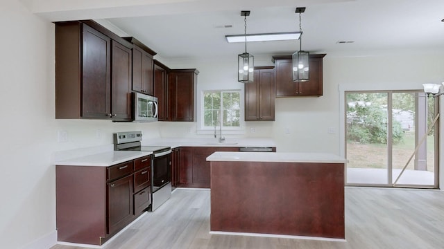 kitchen with pendant lighting, light hardwood / wood-style floors, a kitchen island, appliances with stainless steel finishes, and sink