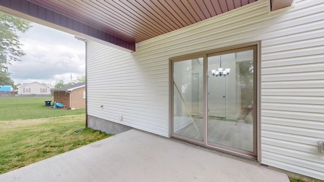 view of exterior entry featuring a patio and a lawn