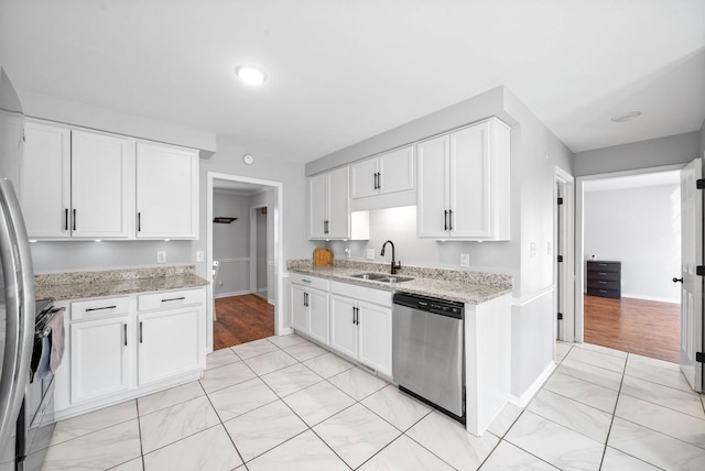 kitchen with light stone countertops, appliances with stainless steel finishes, sink, and white cabinetry