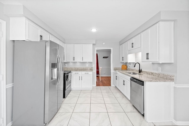 kitchen with light stone counters, sink, white cabinetry, and stainless steel appliances