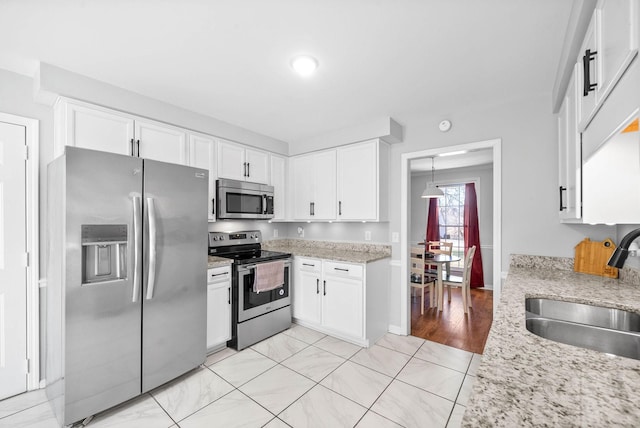 kitchen featuring light stone countertops, sink, white cabinetry, and appliances with stainless steel finishes