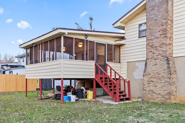 rear view of property with a yard and a sunroom