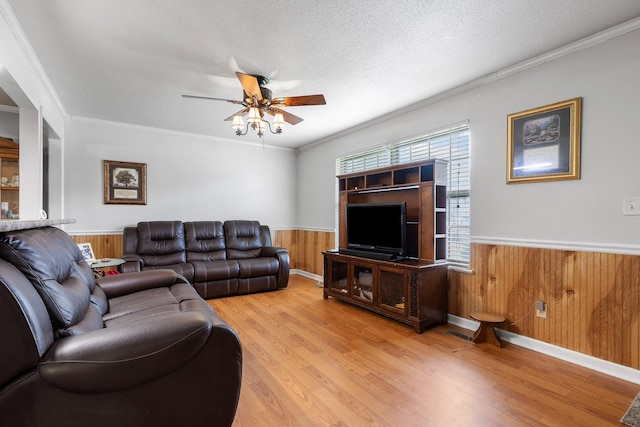 living room with ceiling fan, light hardwood / wood-style floors, a textured ceiling, and crown molding