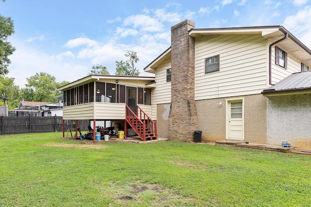 rear view of property featuring a yard and a sunroom