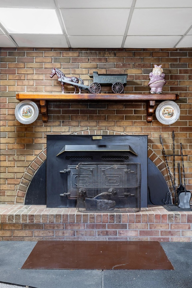 interior details with a wood stove and a drop ceiling