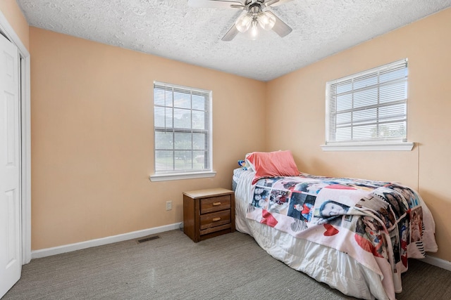 carpeted bedroom featuring a textured ceiling, ceiling fan, and multiple windows