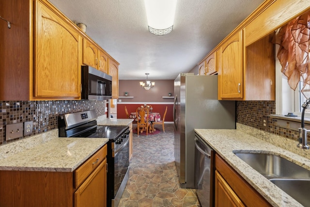 kitchen featuring an inviting chandelier, appliances with stainless steel finishes, sink, decorative light fixtures, and tasteful backsplash