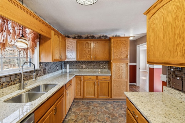 kitchen with light stone counters, decorative backsplash, and sink