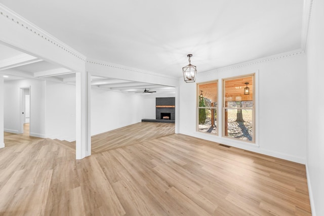 unfurnished living room featuring a large fireplace, crown molding, a chandelier, and light hardwood / wood-style flooring