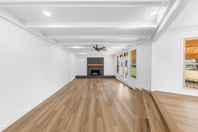 unfurnished living room with ceiling fan, a fireplace, hardwood / wood-style floors, beam ceiling, and ornamental molding