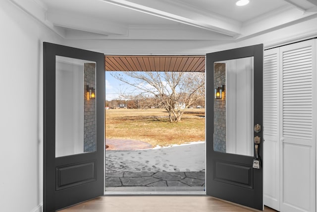 entryway with wood-type flooring, crown molding, and beam ceiling