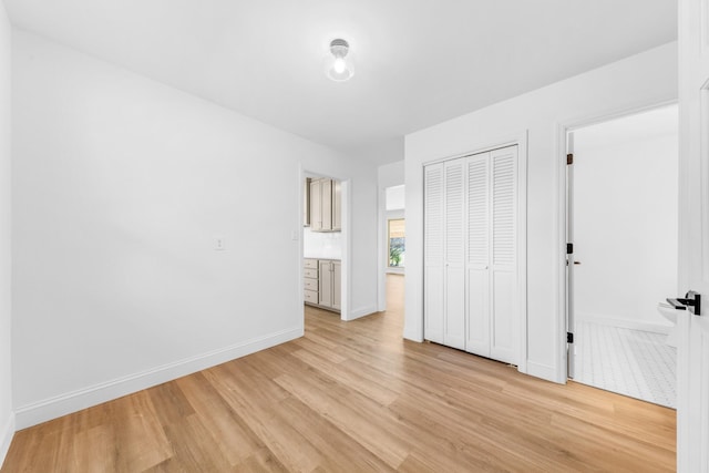 unfurnished bedroom featuring light hardwood / wood-style floors, ensuite bathroom, and a closet