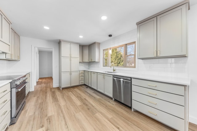 kitchen featuring decorative light fixtures, decorative backsplash, sink, gray cabinetry, and stainless steel appliances