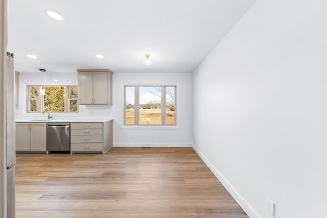 kitchen with light hardwood / wood-style floors, appliances with stainless steel finishes, gray cabinetry, backsplash, and sink