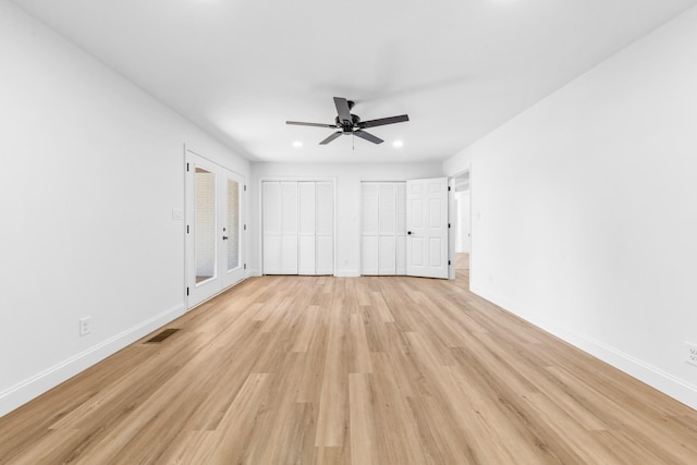 unfurnished bedroom featuring light wood-type flooring, ceiling fan, and two closets