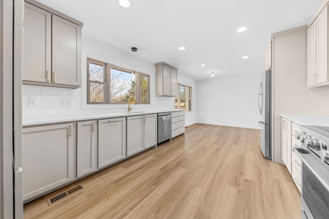 kitchen with decorative light fixtures, sink, gray cabinets, and stainless steel appliances