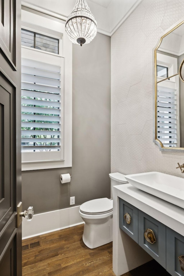 bathroom with a notable chandelier, wood-type flooring, vanity, and toilet