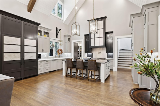 kitchen with a kitchen breakfast bar, hanging light fixtures, a center island, decorative backsplash, and beam ceiling