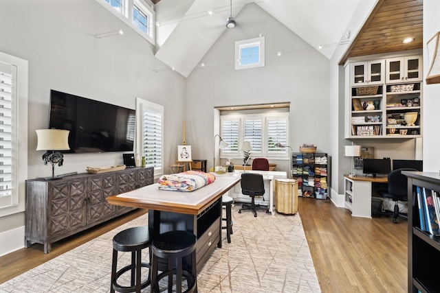 dining area with high vaulted ceiling and light hardwood / wood-style floors