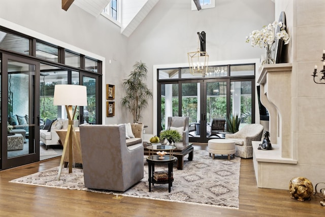 living room featuring beamed ceiling, french doors, hardwood / wood-style flooring, a high ceiling, and a notable chandelier